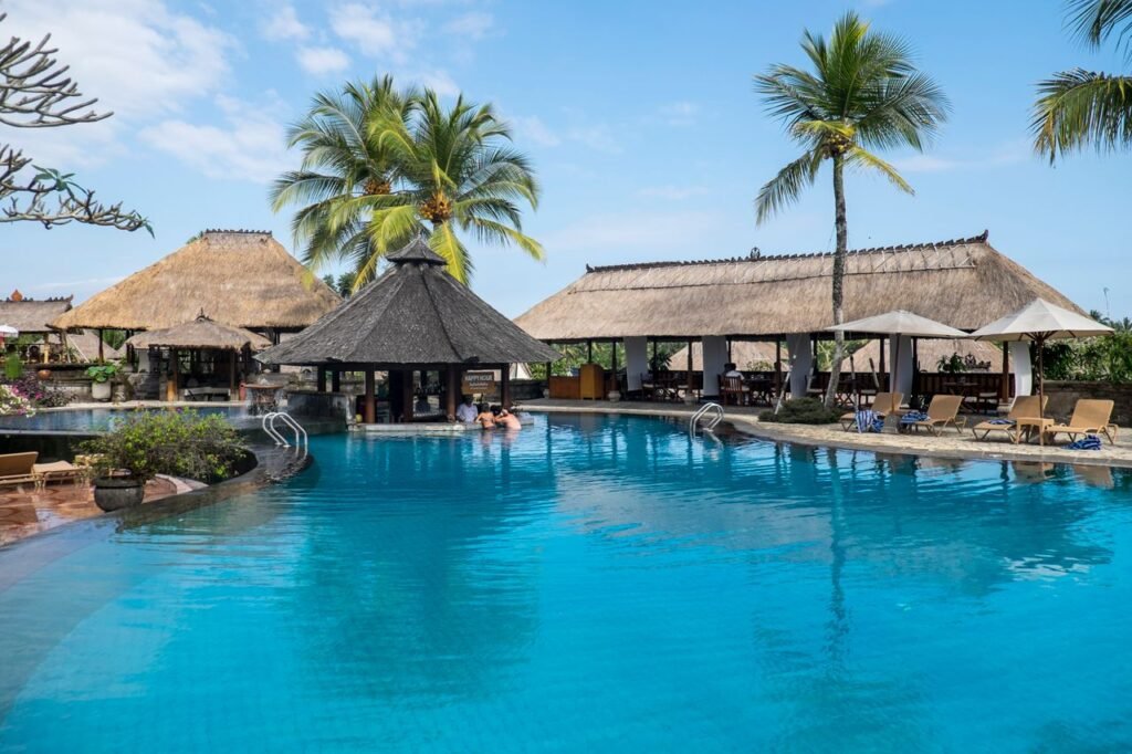 pexels-photo-2259226-2259226 Relax by the tropical pool at a luxurious resort in Bali, featuring palm trees and serene blue waters.